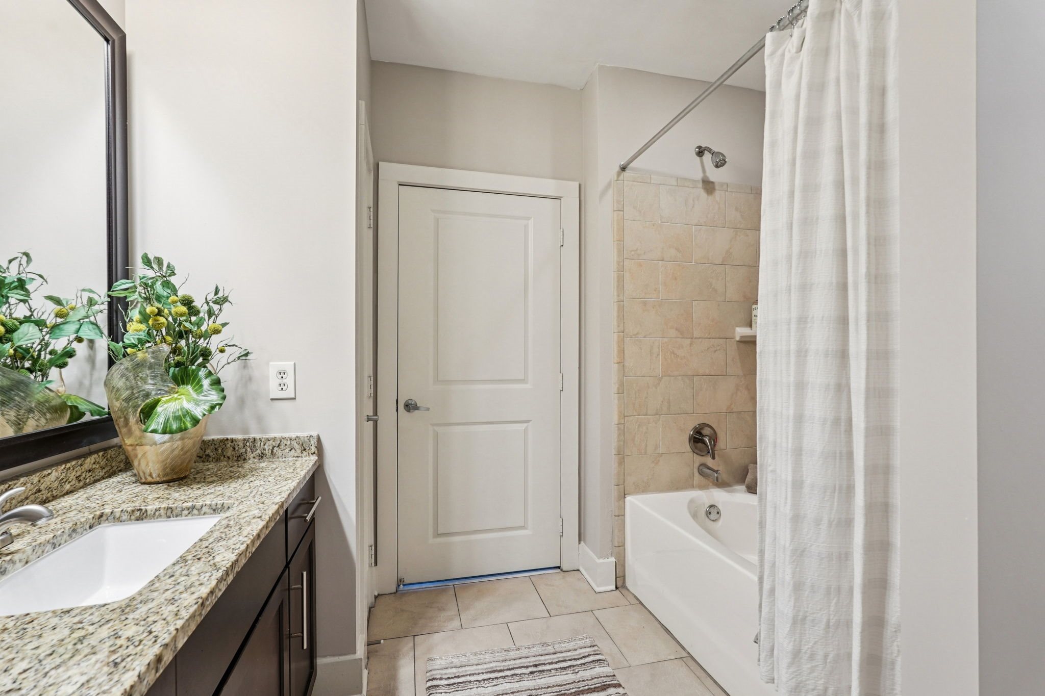 A bathroom with a white door, a white tub, and a white shower curtain.